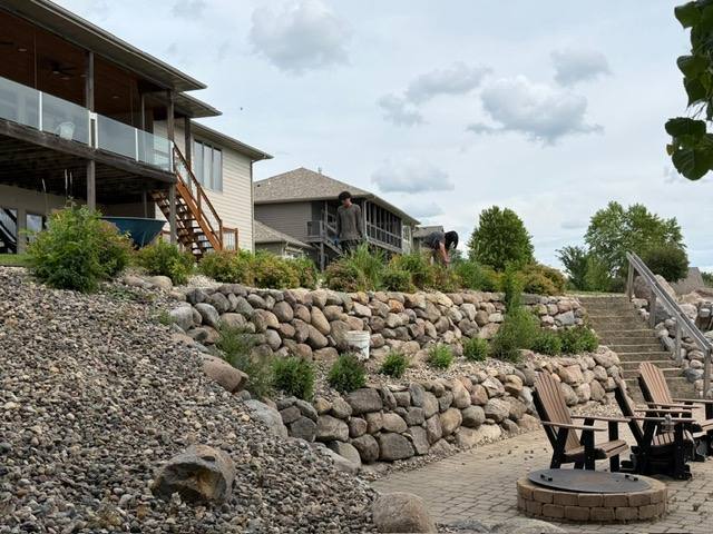 Boulder retaining wall with a fire pit seating area on a landscaped slope