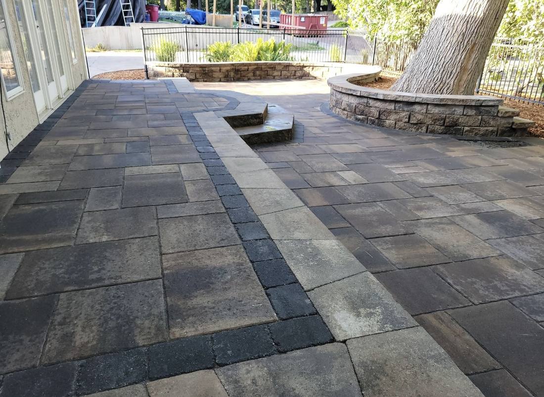 Large paver patio with decorative banding, seating wall, and fire feature