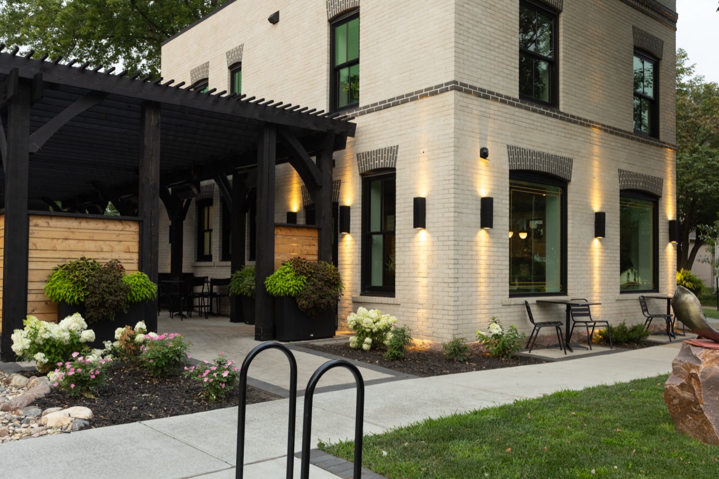 Pergola patio with uplit facade and plantings at The Perch