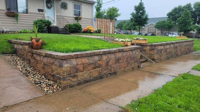 Block retaining wall with a raised turf lawn and decorative rock drainage